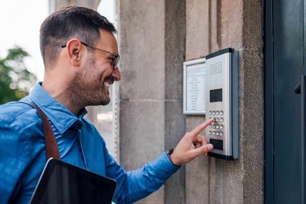 smiling man pressing bottoms on the intercom