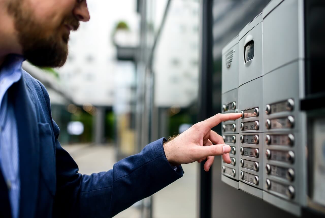 man pushing intercom buttons to enter the building
