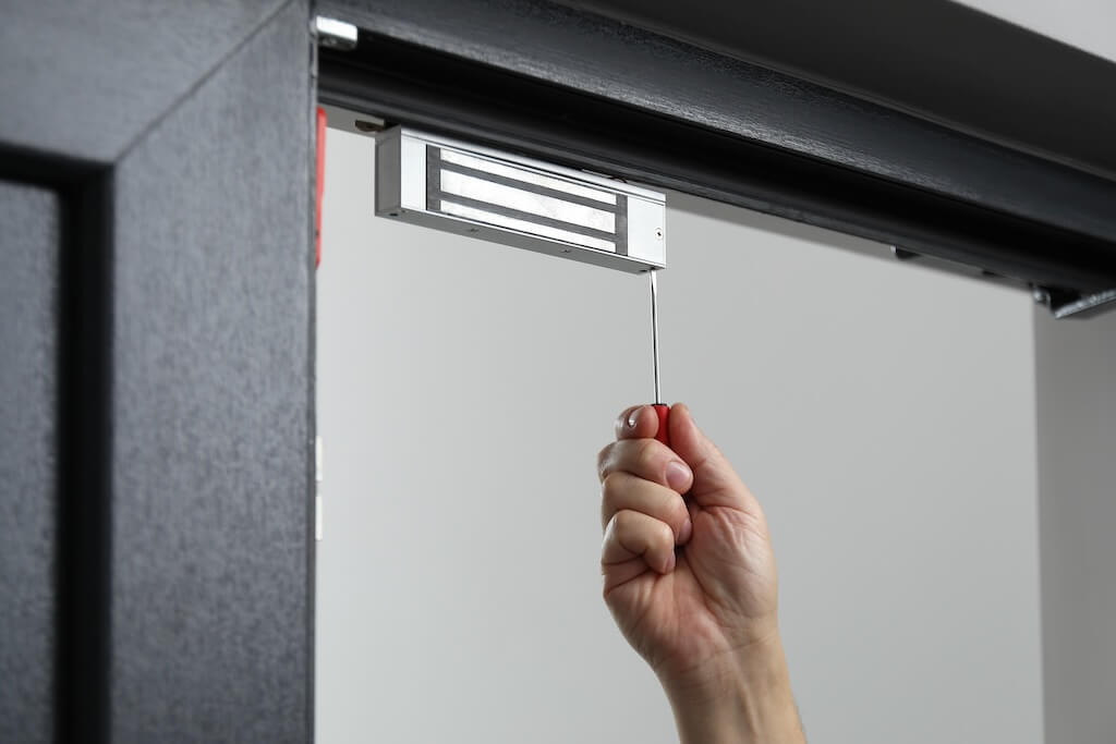 Man with screwdriver installing electromagnetic door lock indoors