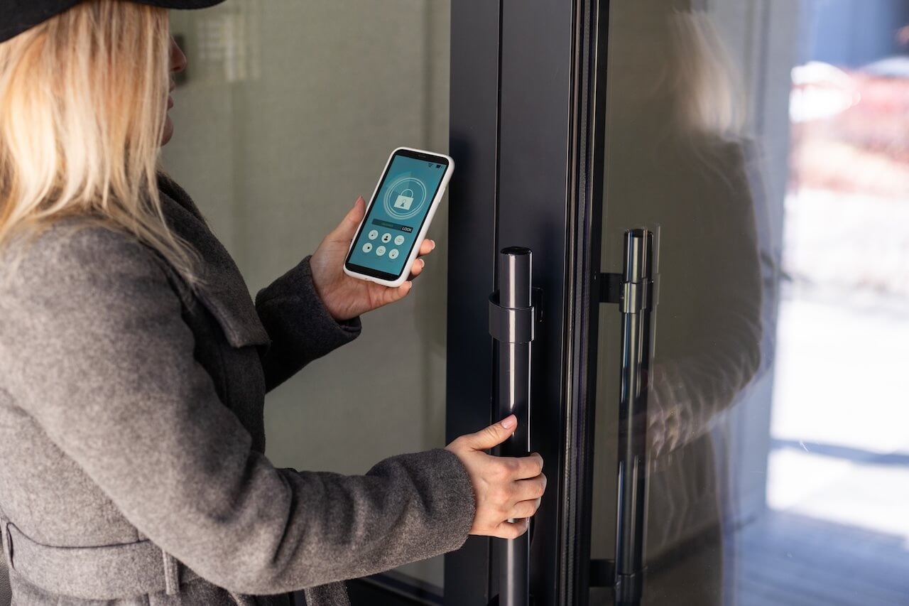Woman locking smartlock on the entrance door using a smart phone