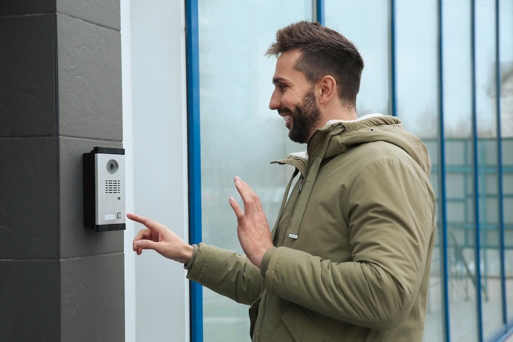 man ringing intercom while waving to camer