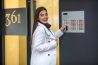 Young business woman in white suit touching the intercom with keyfob