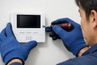 worker uses a screwdriver to secure the wall-mounted intercom monitor