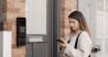 Woman using a mobile phone app to access a building intercom panel