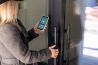 Woman locking smartlock on the entrance door using a smart phone