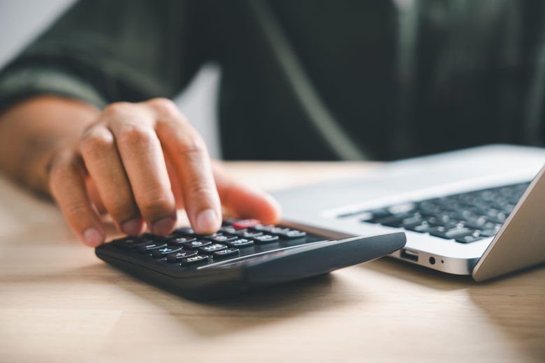 a person's hand using a calculator for budgeting and estimating total cost