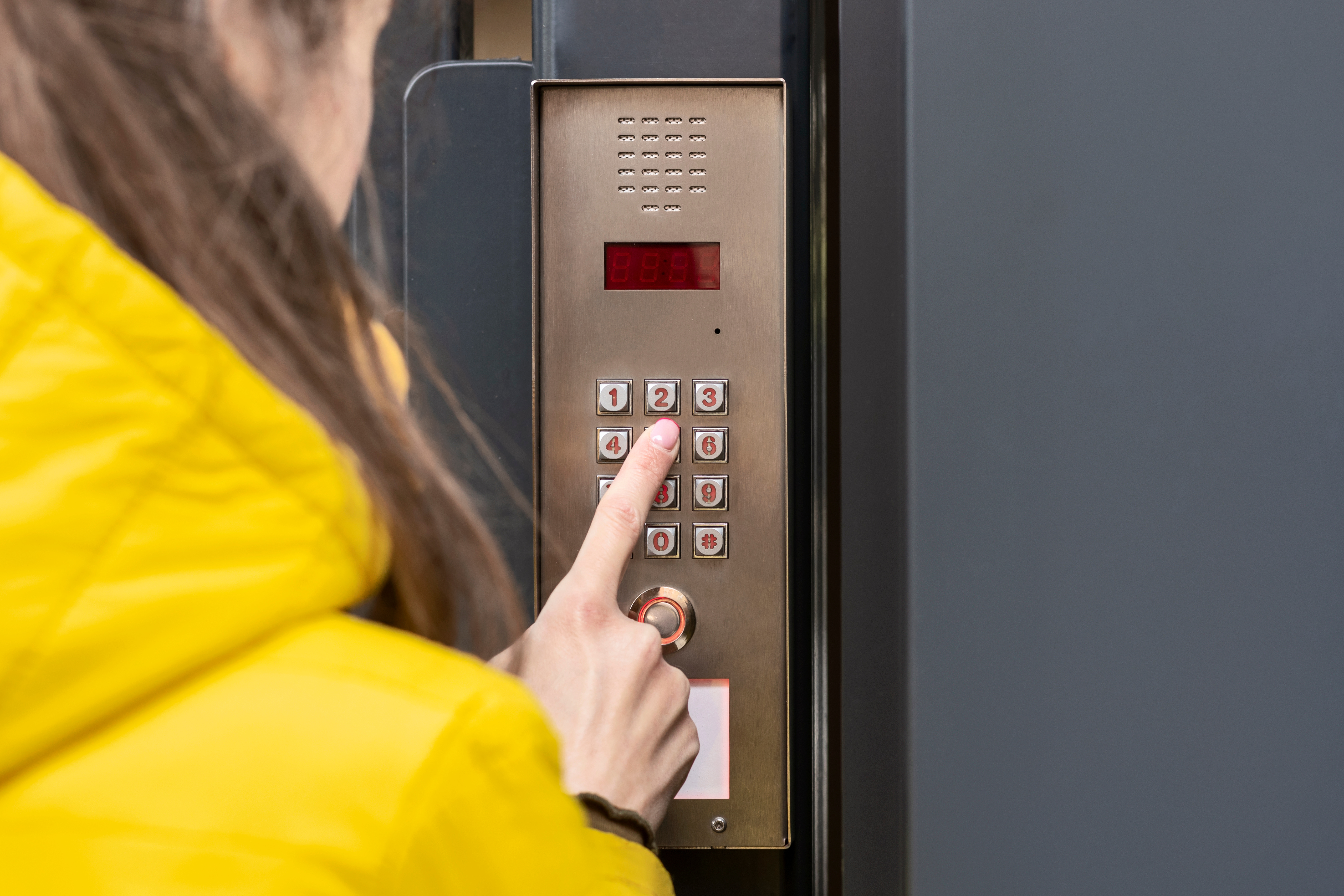 woman pressing PIN code on telephone entry system